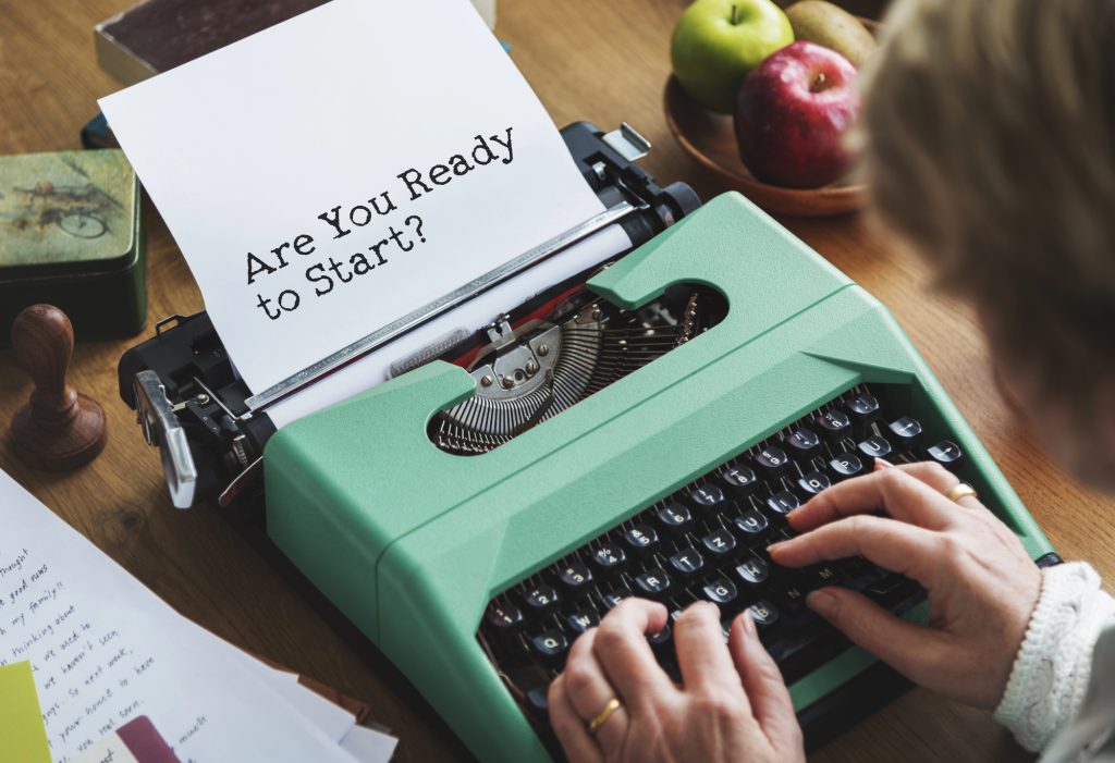 Someone is typing on a typewriter with "Are you ready to start?" written on the paper.

